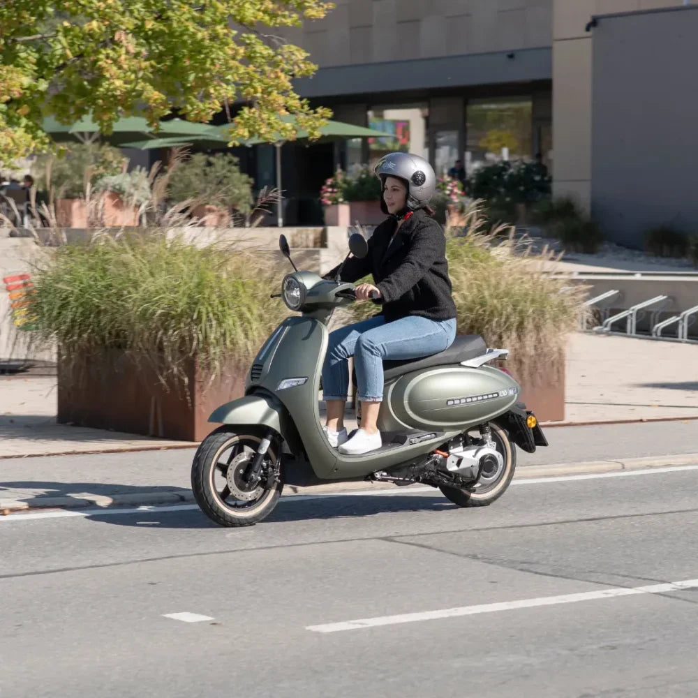 Oseba se vozi z električnim skuterjem Efo Et5000 po mestni ulici.