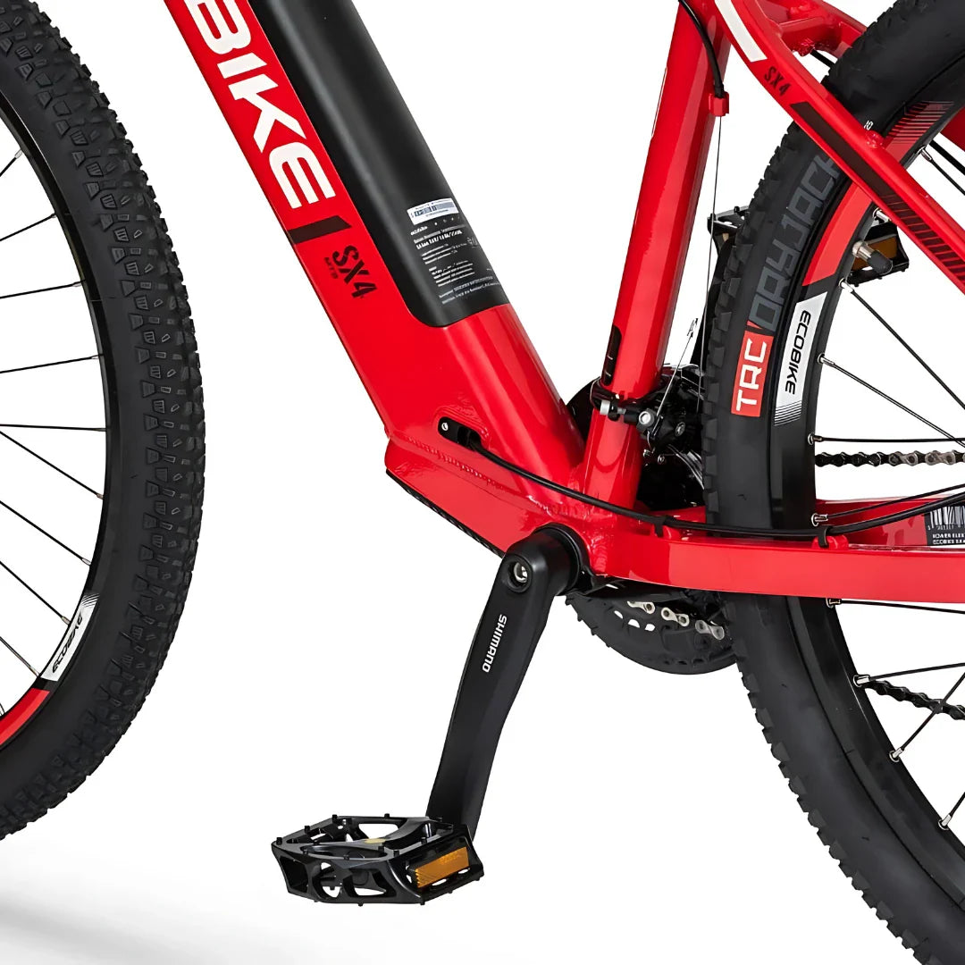 Izdelek na sliki je električno kolo znamke Ecobike, model SX4. Na sliki je vidna rdeča okvirna konstrukcija kolesa, skupaj s pedali, ki so opremljeni z znamko Shimano. Kolo ima široke pnevmatike, kar nakazuje na primernost za terensko vožnjo. Vidna je tudi baterija, ki je integrirana v okvir, kar prispeva k estetskemu videzu in funkcionalnosti kolesa.