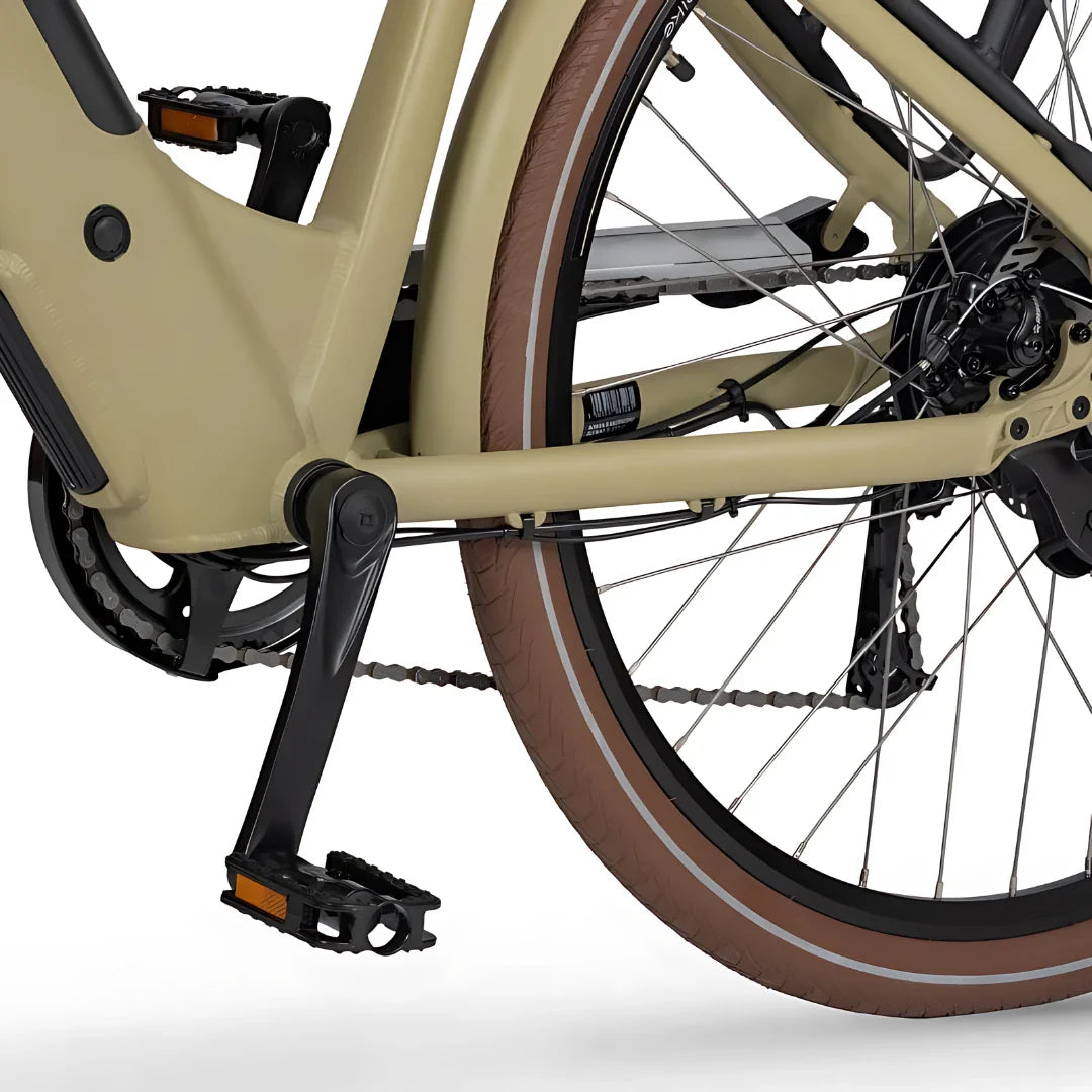 Izdelek je električno kolo znamke Ecobike, model X-City. Na sliki je prikazan del okvirja, pedal in zadnje kolo kolesa. Barva okvirja je svetla, kolo pa ima rjave pnevmatike z belim obodom. Vidna je tudi veriga in del mehanizma za prestavljanje.